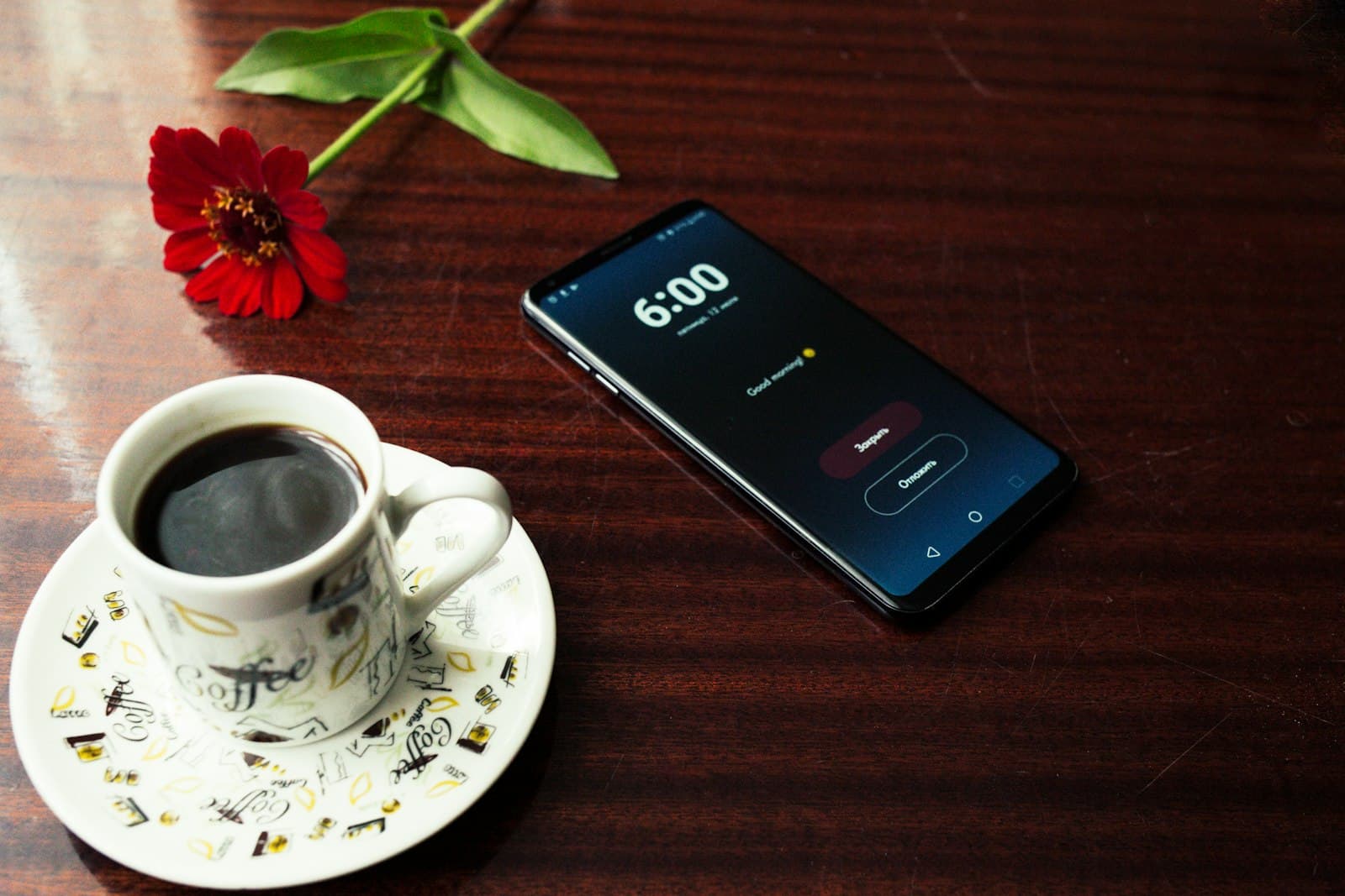 A cup of coffee and a phone on a wooden table in the morning