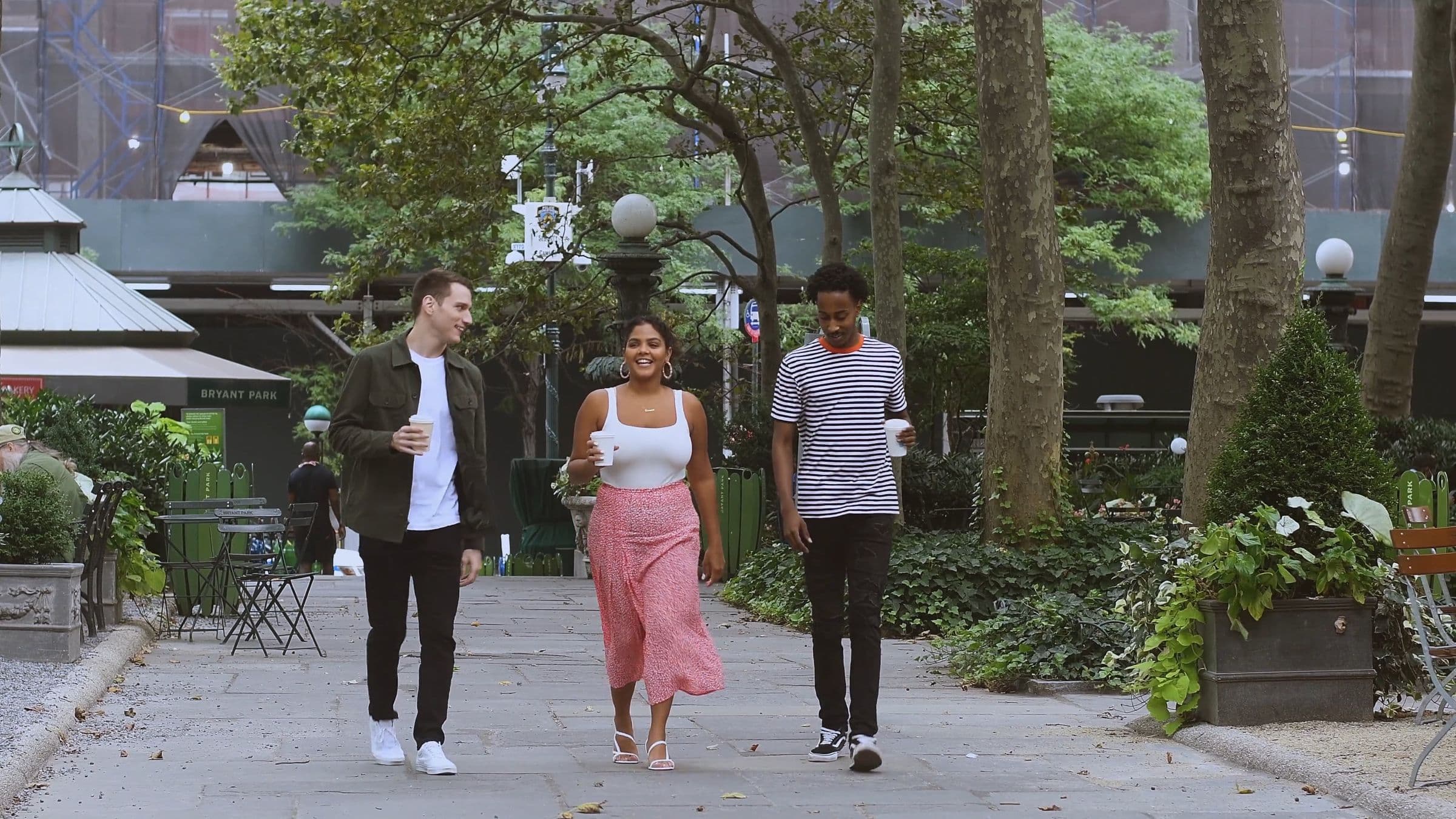 Three friends walking together through a city park